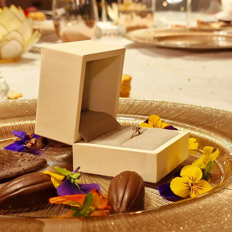 Écrin en bois contenant un bague sertie d'un diamant, posé sur un plateau doré