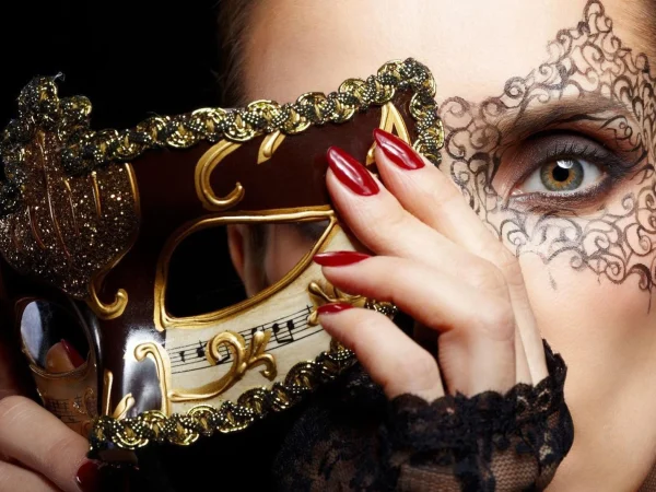 Une femme retire son masque vénitien, on voit son œil avec un dessin décoratif