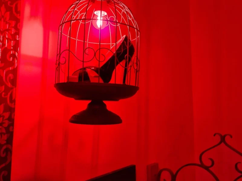 Cage suspendue avec un soulier sexy enfermé dans une ambiance lumière rouge