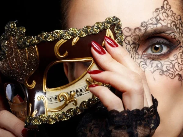 Une femme retire son masque vénitien, on voit son œil avec un dessin décoratif